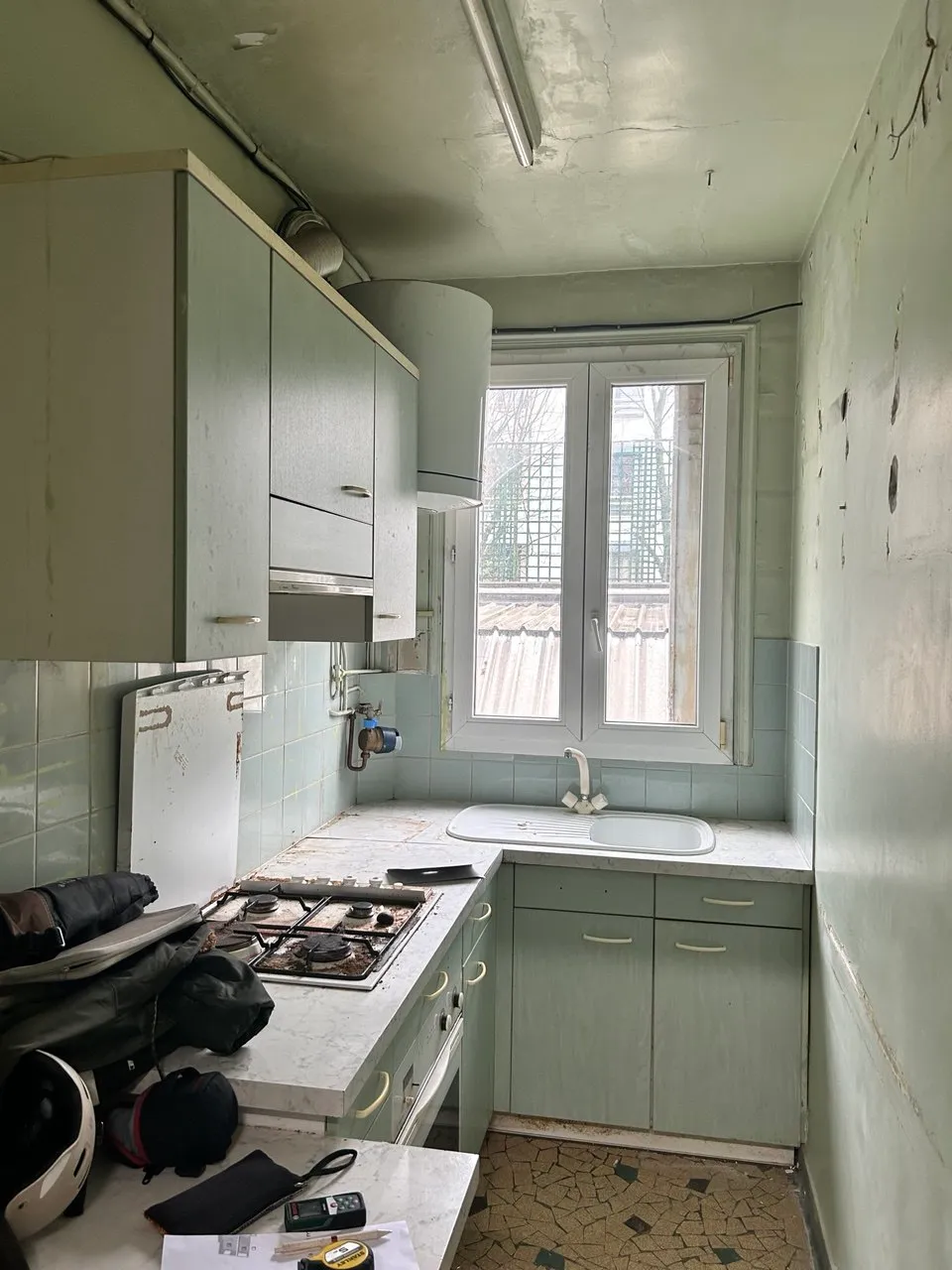 La cuisine avant travaux, avec ses meubles vert d'eau et son carrelage mosaïque d'origine