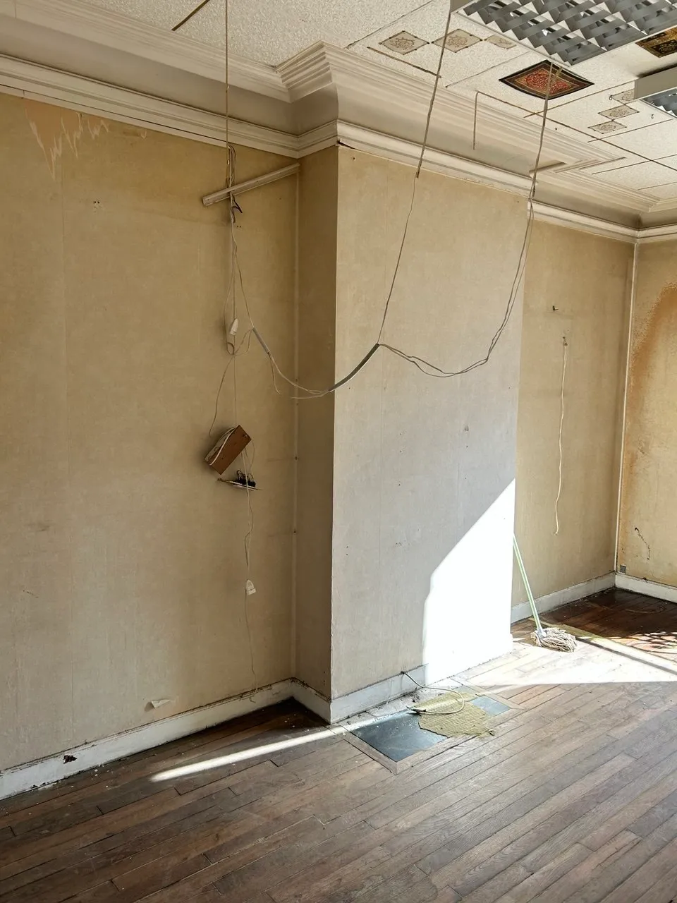 La pièce de vie avant travaux : murs décapés, câbles apparents et plafond à caissons d'origine